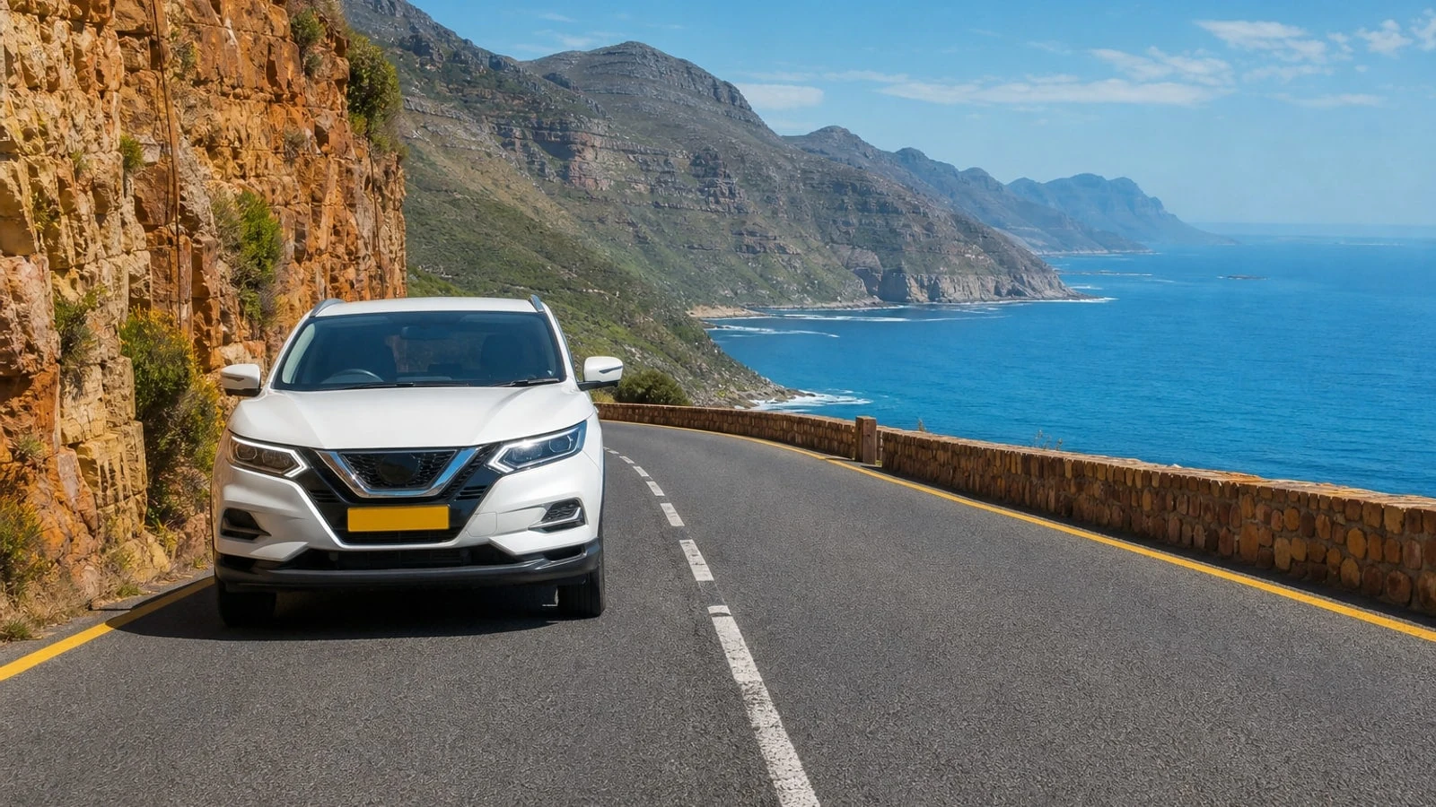 White RHD SUV approaching in the left lane on a Cape Town coastal mountain road — car insurance broker versus going direct in South Africa